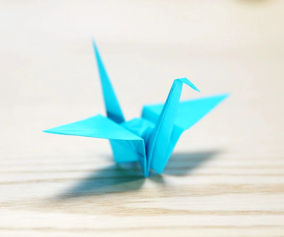 A blue origami bird on a wood surface

Description automatically generated
