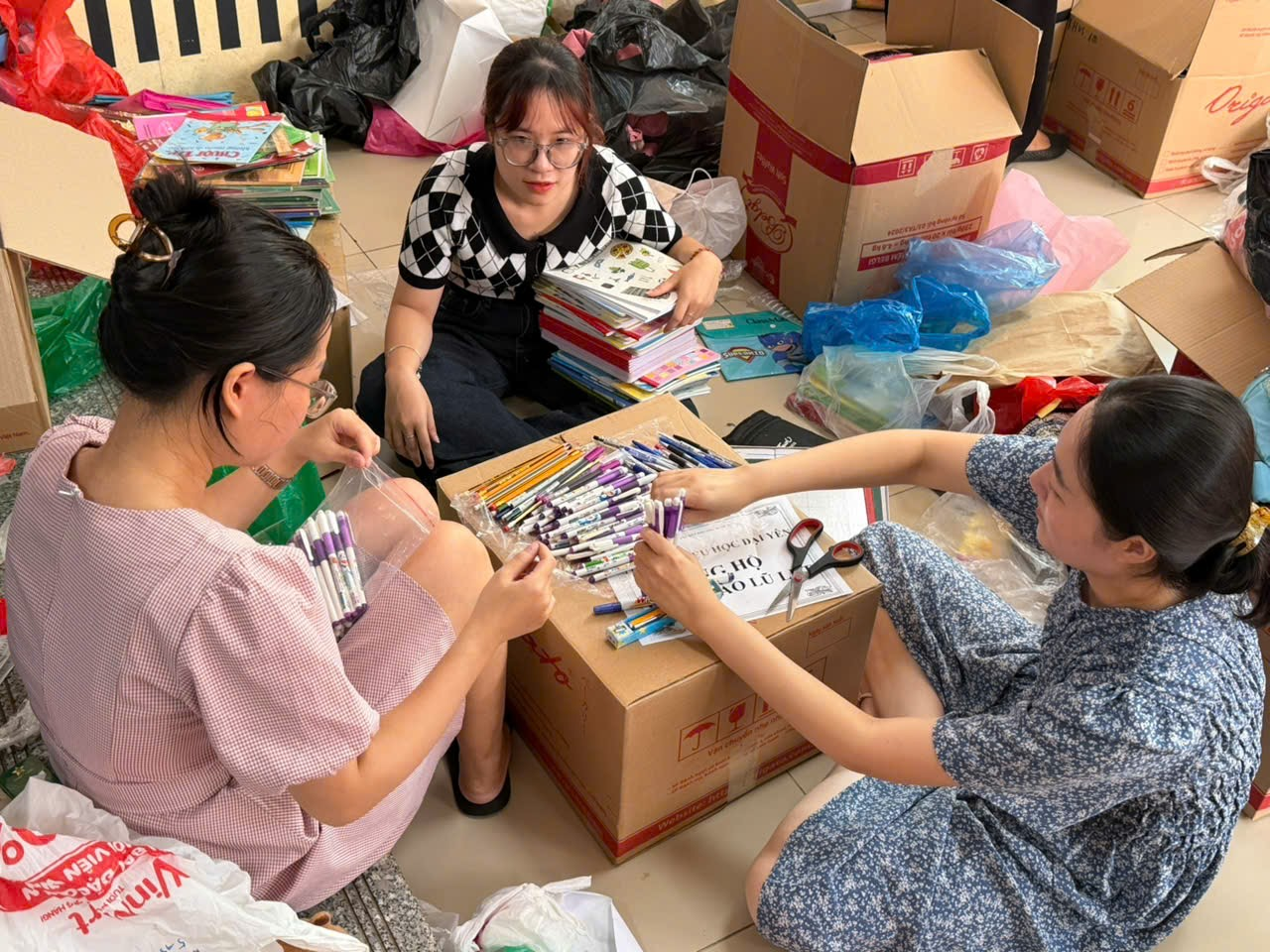 A group of women sitting on the floor with boxes and books

AI-generated content may be incorrect.