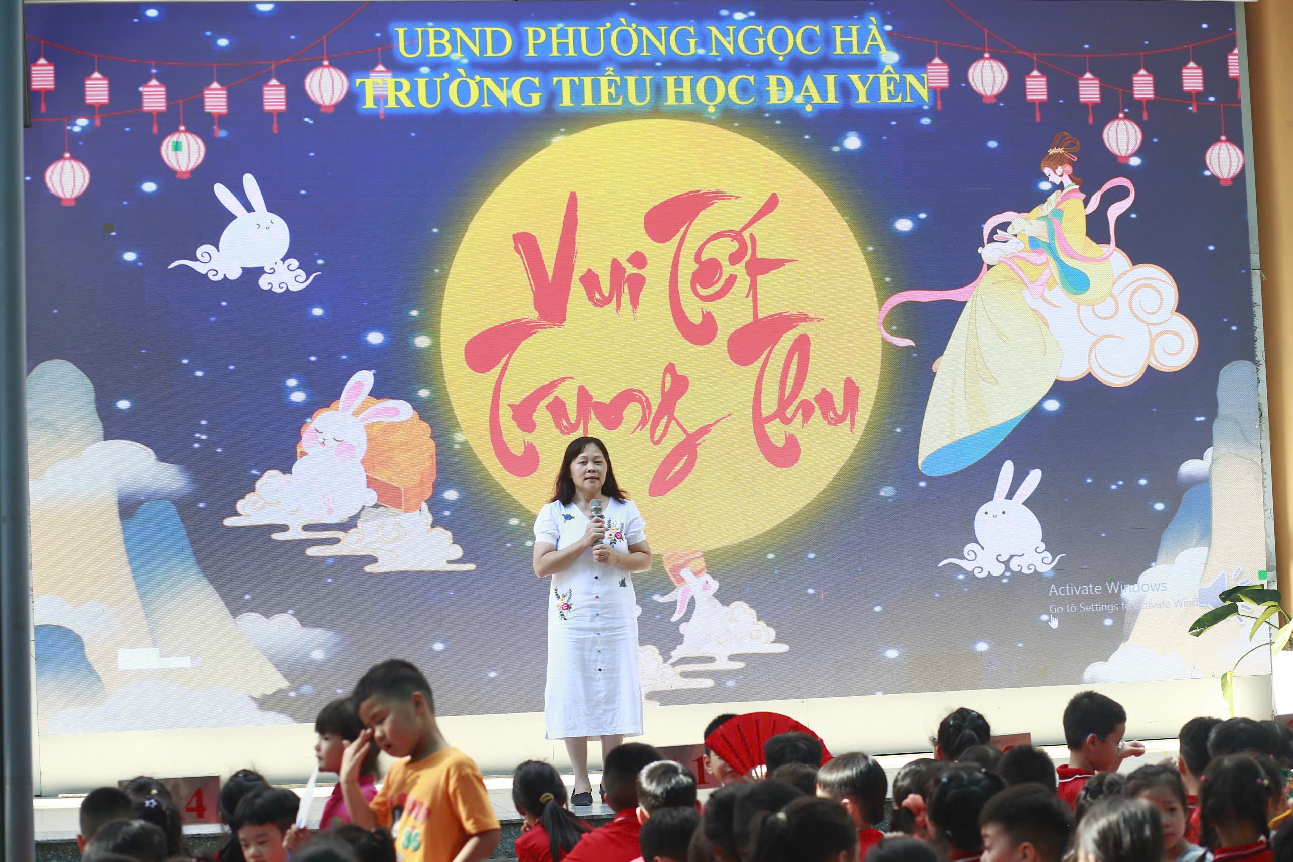 A person standing on a stage with a large screen with a large moon and cartoon characters
AI-generated content may be incorrect.