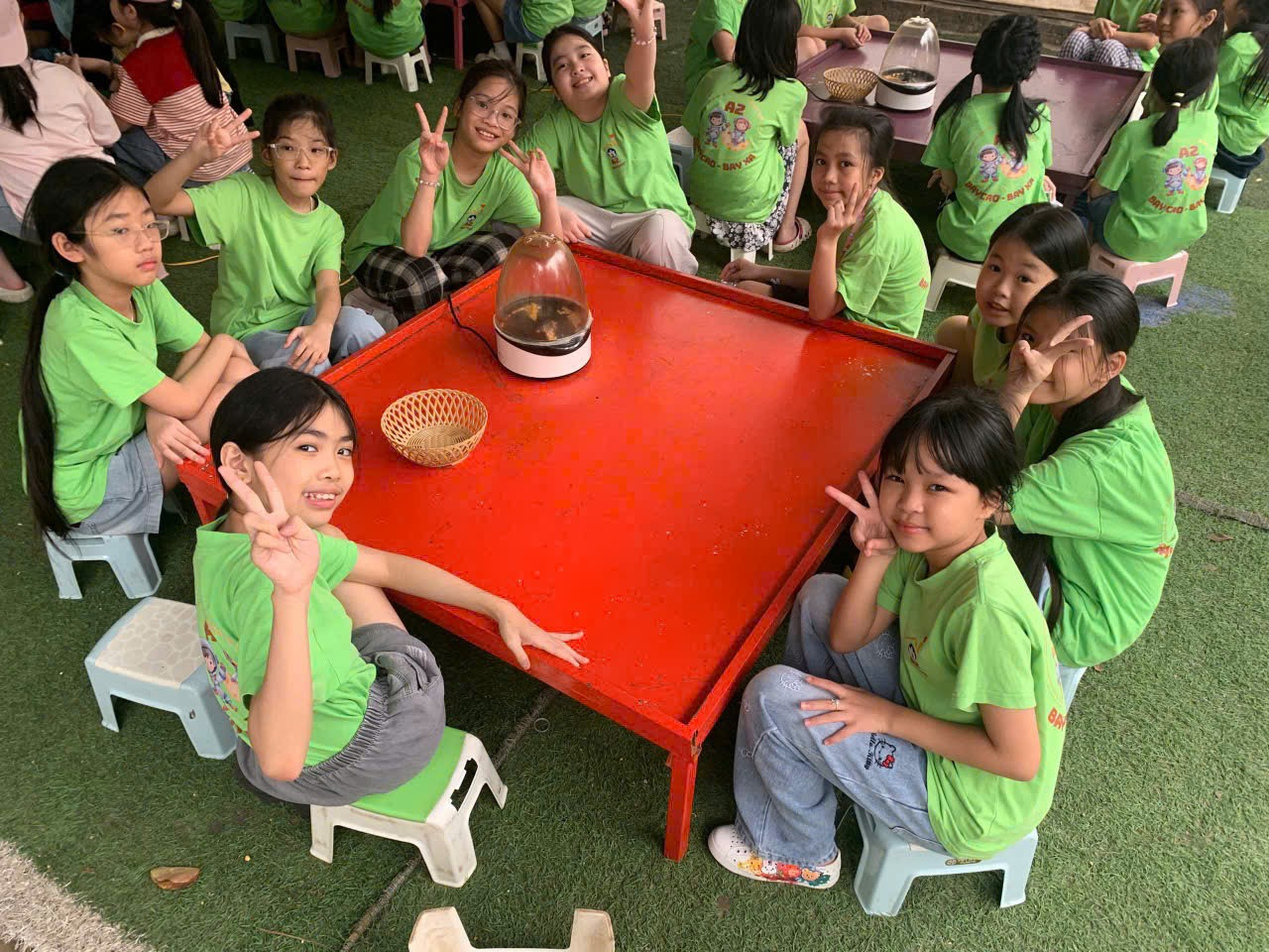 A group of children sitting around a red table

AI-generated content may be incorrect.