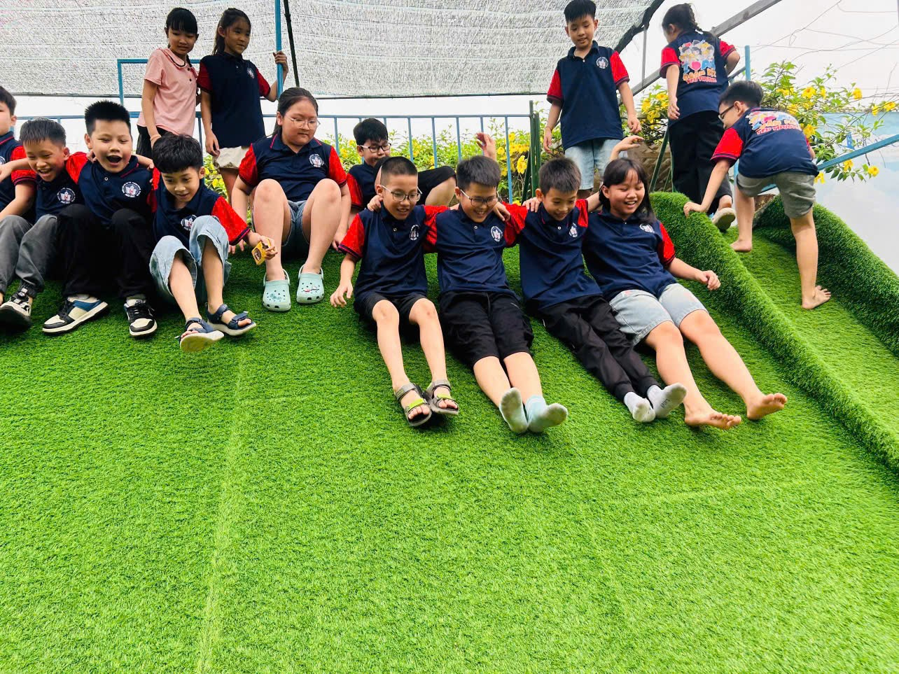 A group of children sitting on a green staircase

AI-generated content may be incorrect.